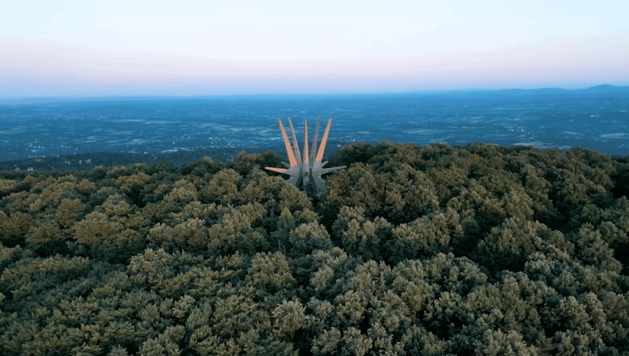 A tower with tall, pointed structures rises above a dense forest, with a distant landscape and sky in the background.