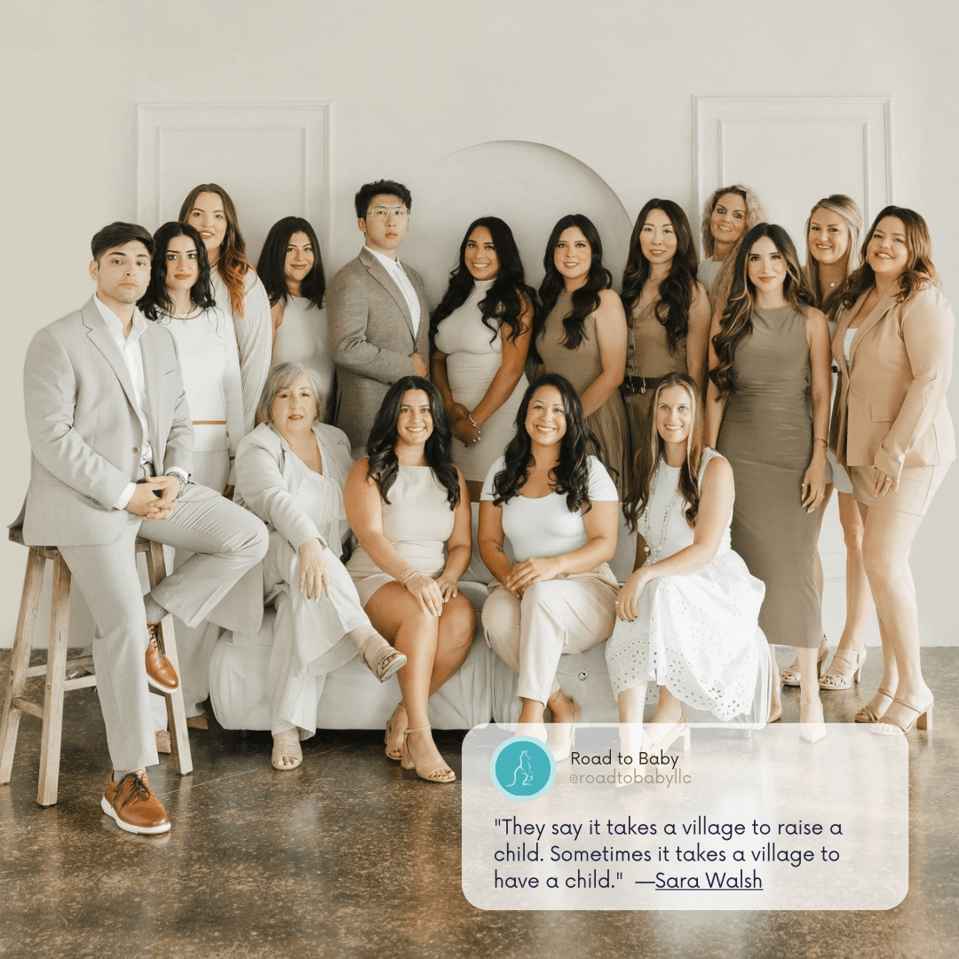 Group of 15 people, mostly women, posing in a bright room with white walls and a sofa, some sitting and some standing.