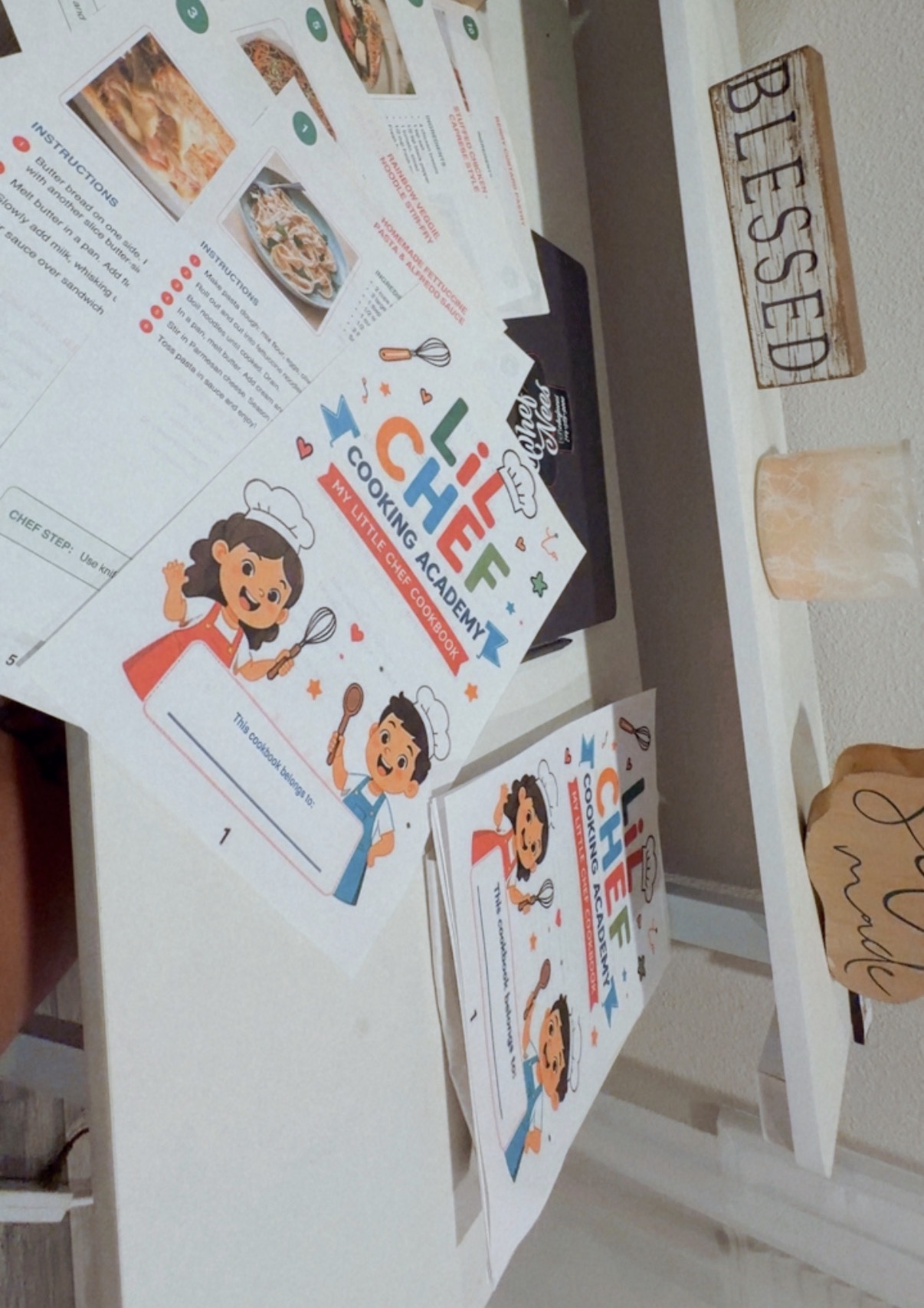 Educational flyers about healthy eating and cooking for children, featuring illustrations of children and food, on a white table.