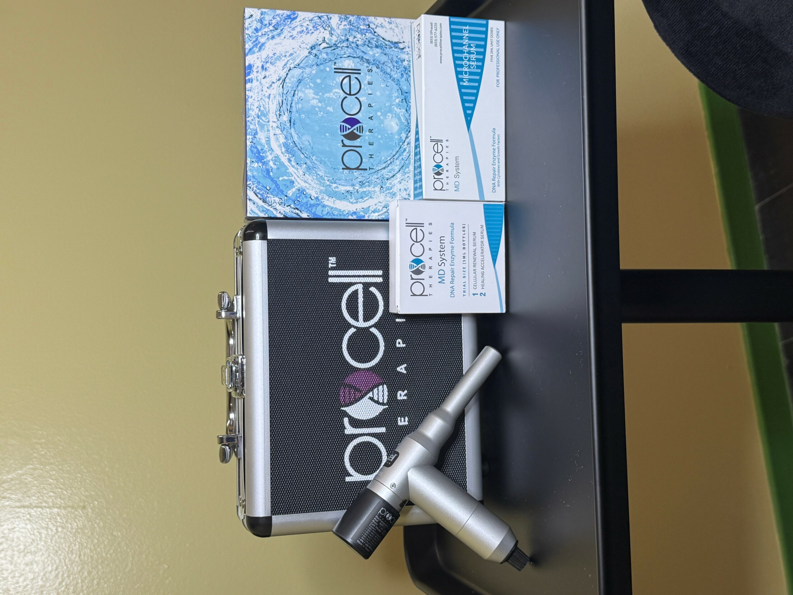 Two boxes of medical products and a silver device on a black surface, with a green and beige background.