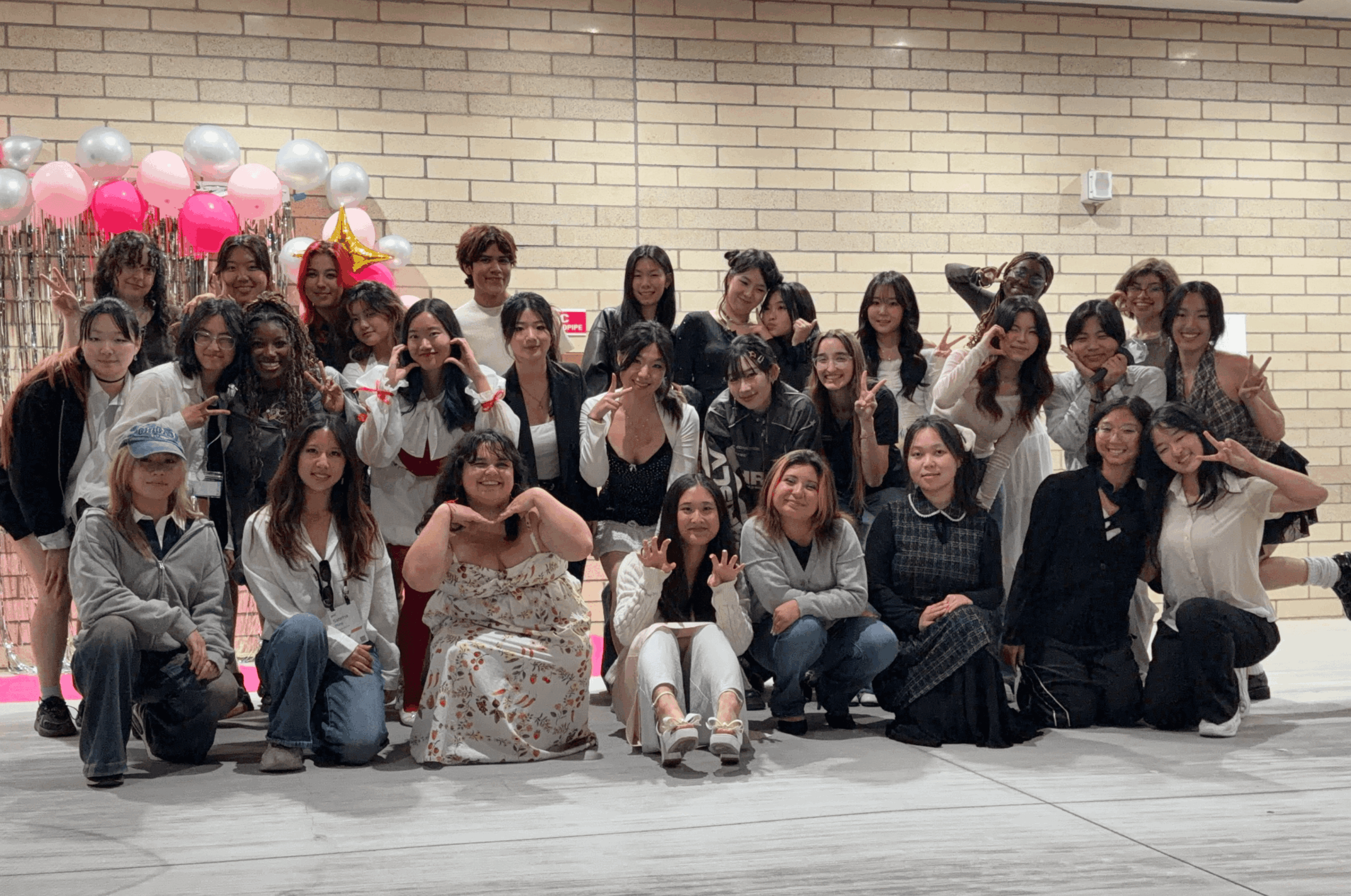 Group of women and children posing indoors with balloons in background.